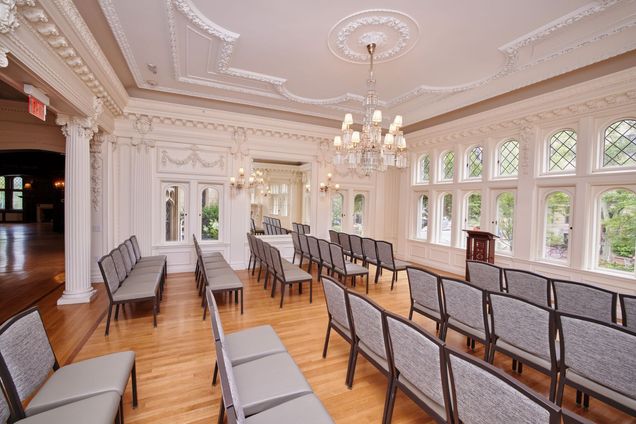 Angled view of Music Room setup lecture style with grey tables & podium at the front.