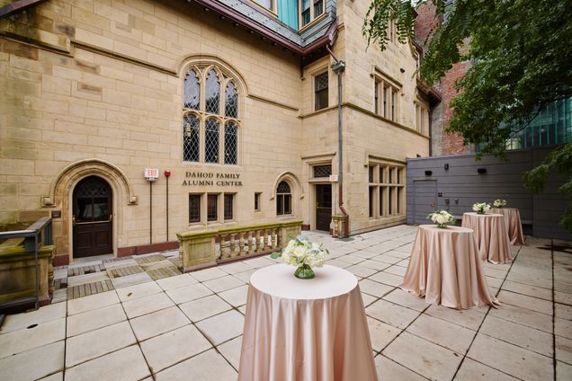 Outdoor terrace patio set with high-top tables with cream linens & flowers with the back view of the Castle.