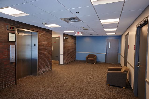Elevator foyer with both brick walls & blue painted walls and brown carpet.