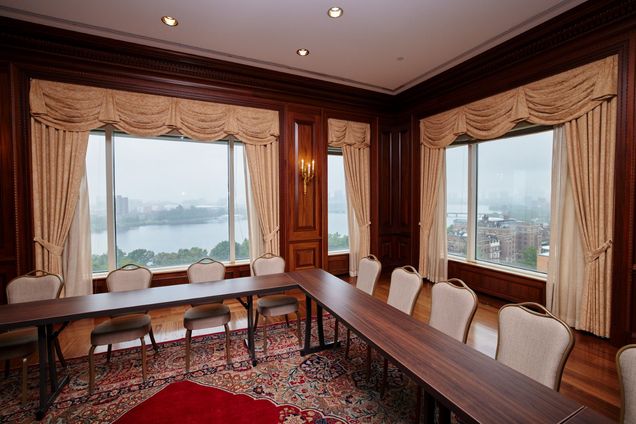Closer view of tables & chairs setup with view of Charles River & Boston in the windows in the background.