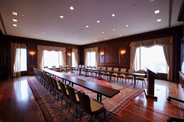 View of an empty Kenmore Room setup in U-shape tables & chairs, with podium at the front.