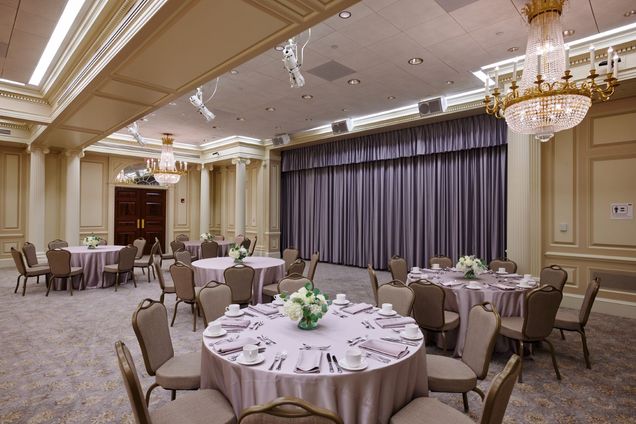 Empty Ballroom setup showing 3 formally pre-set tables for a sit-down meal, close to the front main grey curtain.