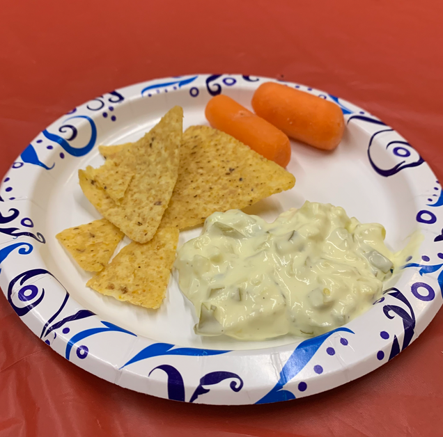 To show dill pickle dip being served along with tortilla chips and carrots.