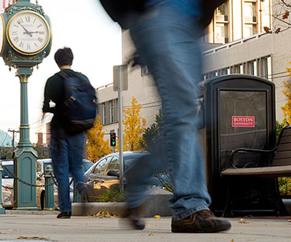 sidewalk level view of people walking on campus