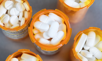 Close up overhead view of full prescription bottles on stainless steel background