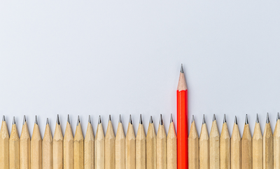 One red pencil sticking out of a group of yellow pencils