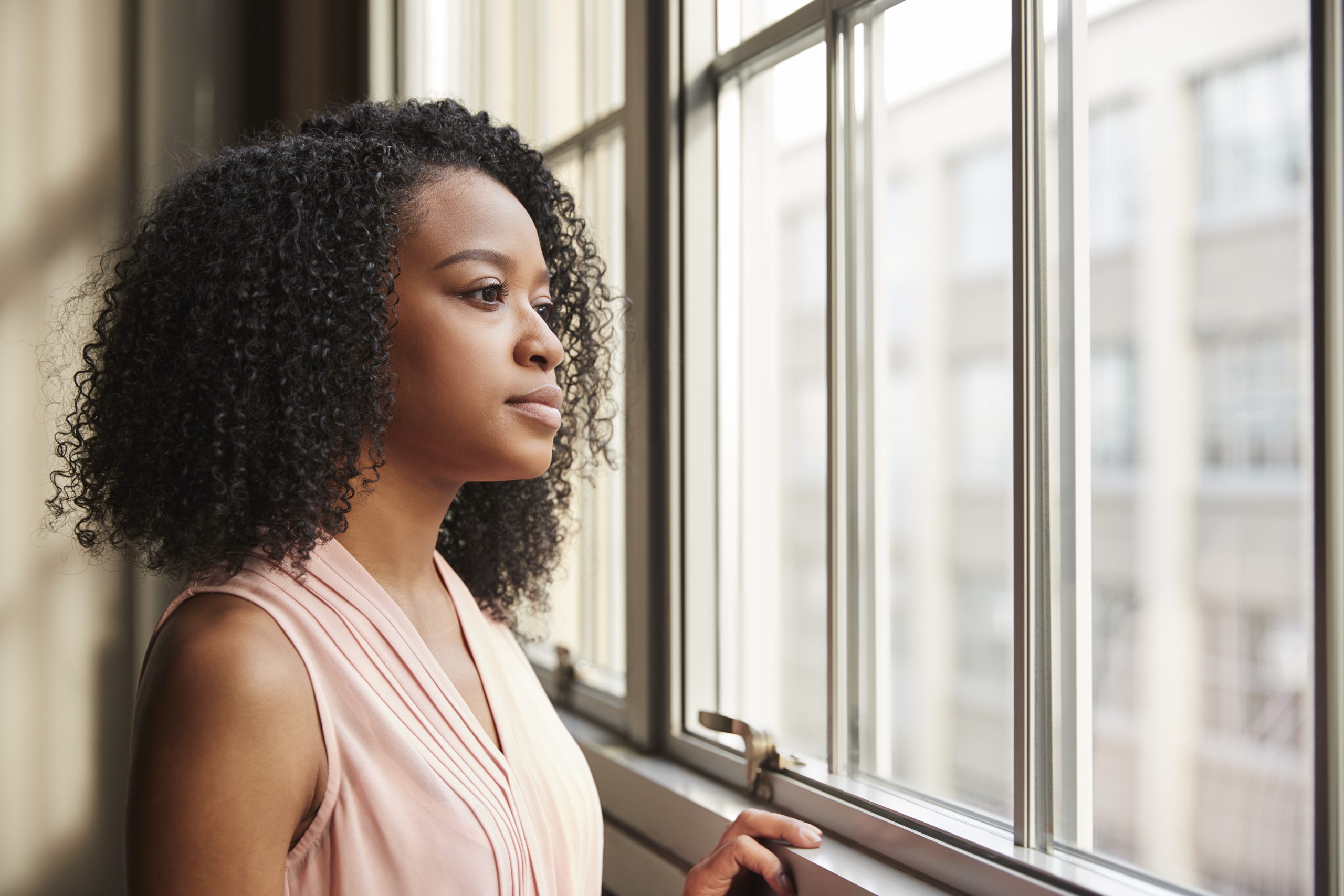 Young black businesswoman looking out of window