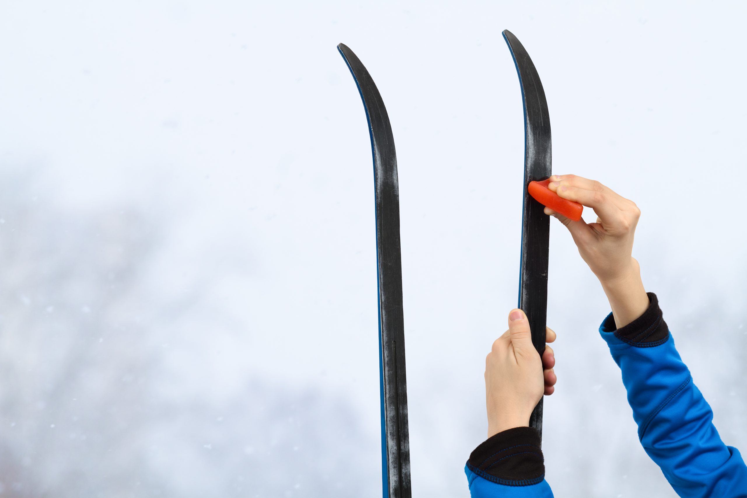 Hands putting wax on skis