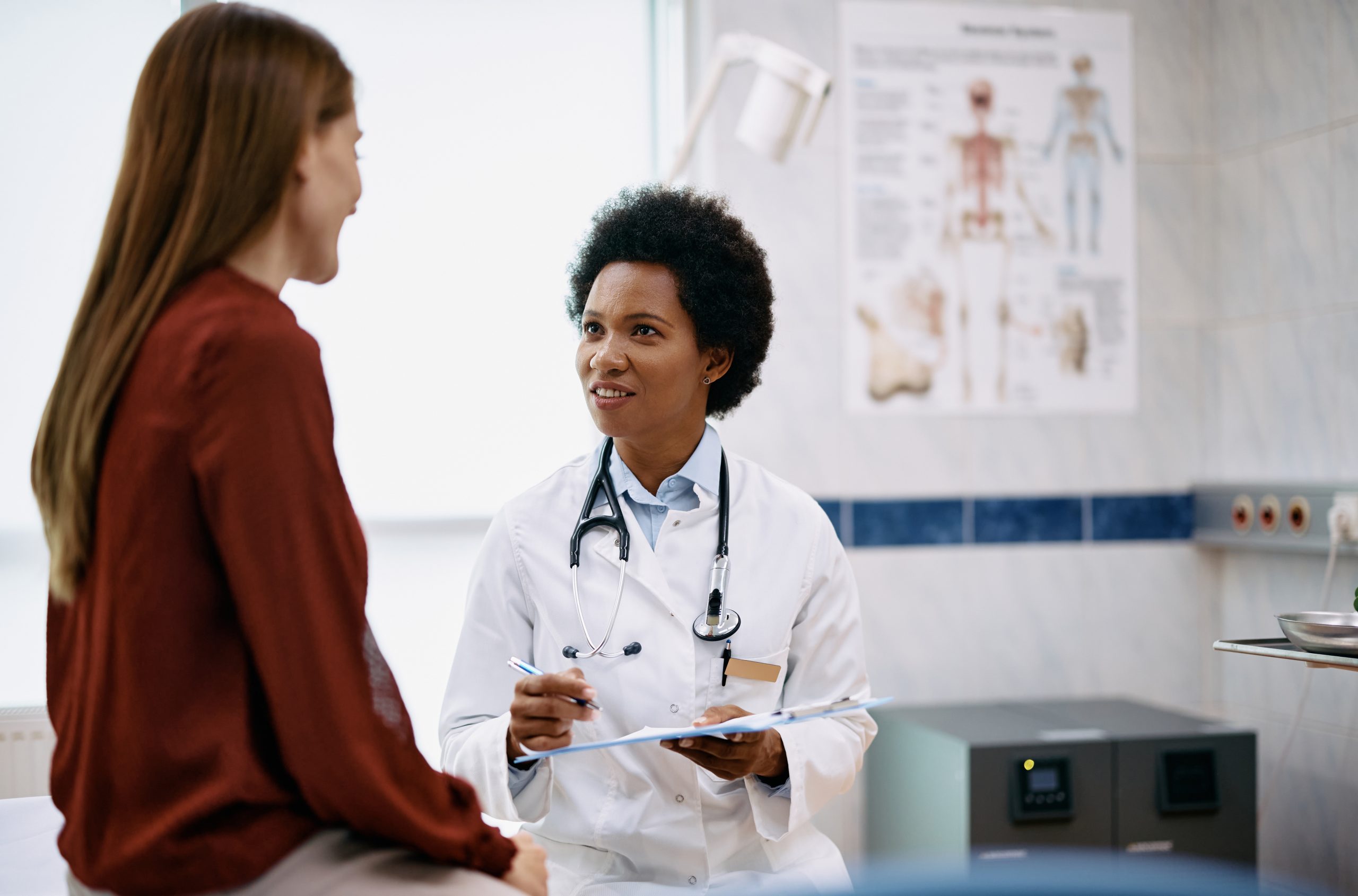 African American doctor and her female patient communicating during examination at medical clinic.