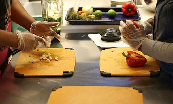 Two people cut up vegetables on cutting boards