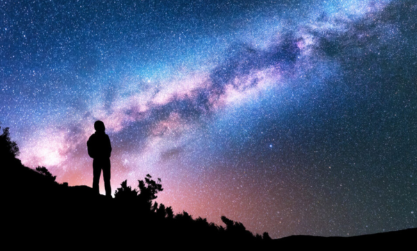 Person stands looking at starry night sky