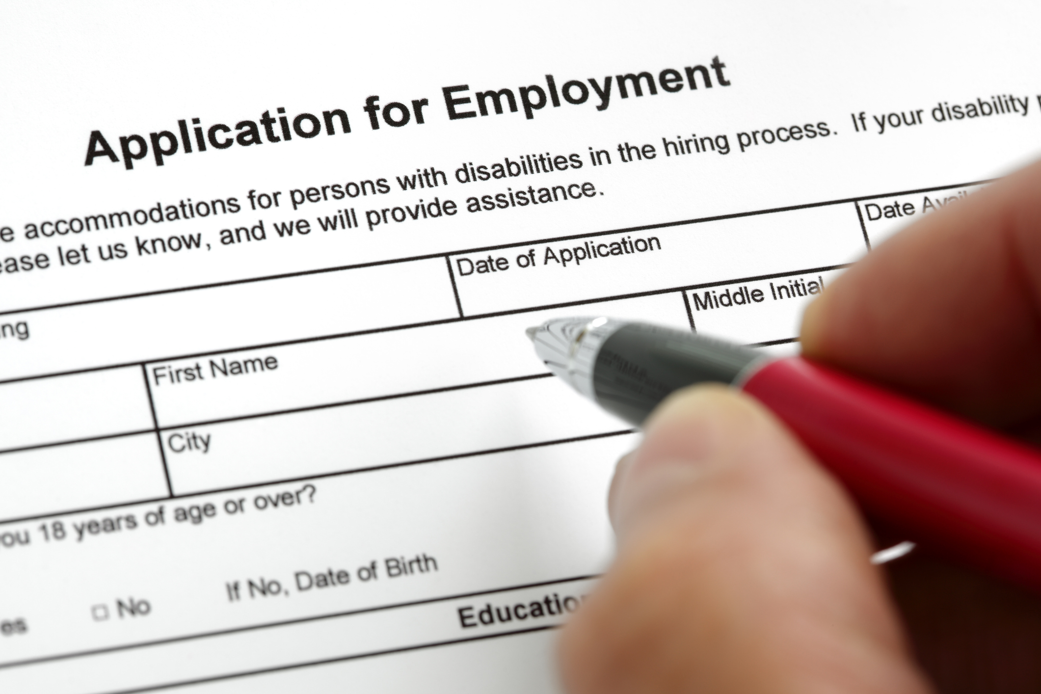 A hand with a pen filling out an application for employment