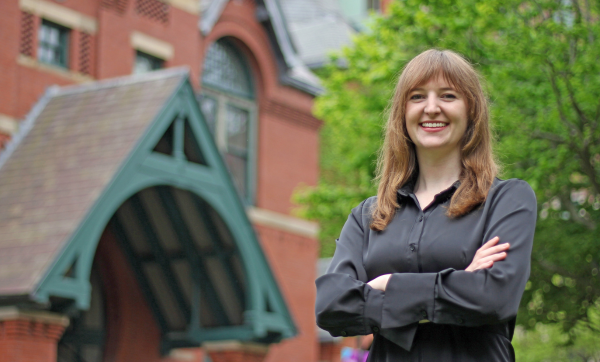 Charlotte Greenhill stands with arms crossed in front of the Talbot Building