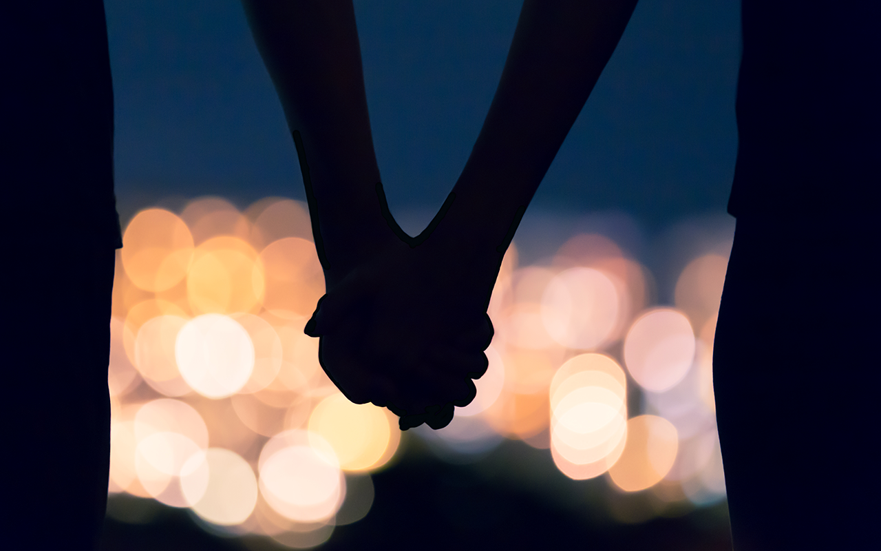 Couple holding hands against city night lights bokeh