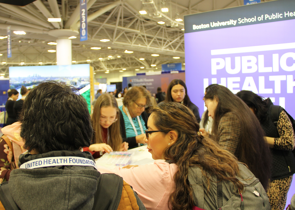 Group of people making friendship bracelets at SPH booth at APHA