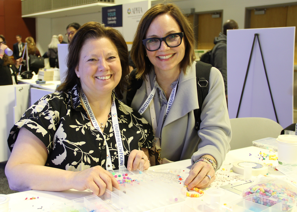 Mary Murphy-Phillips and Julia Lanham making friendship bracelets at the SPH booth at APHA