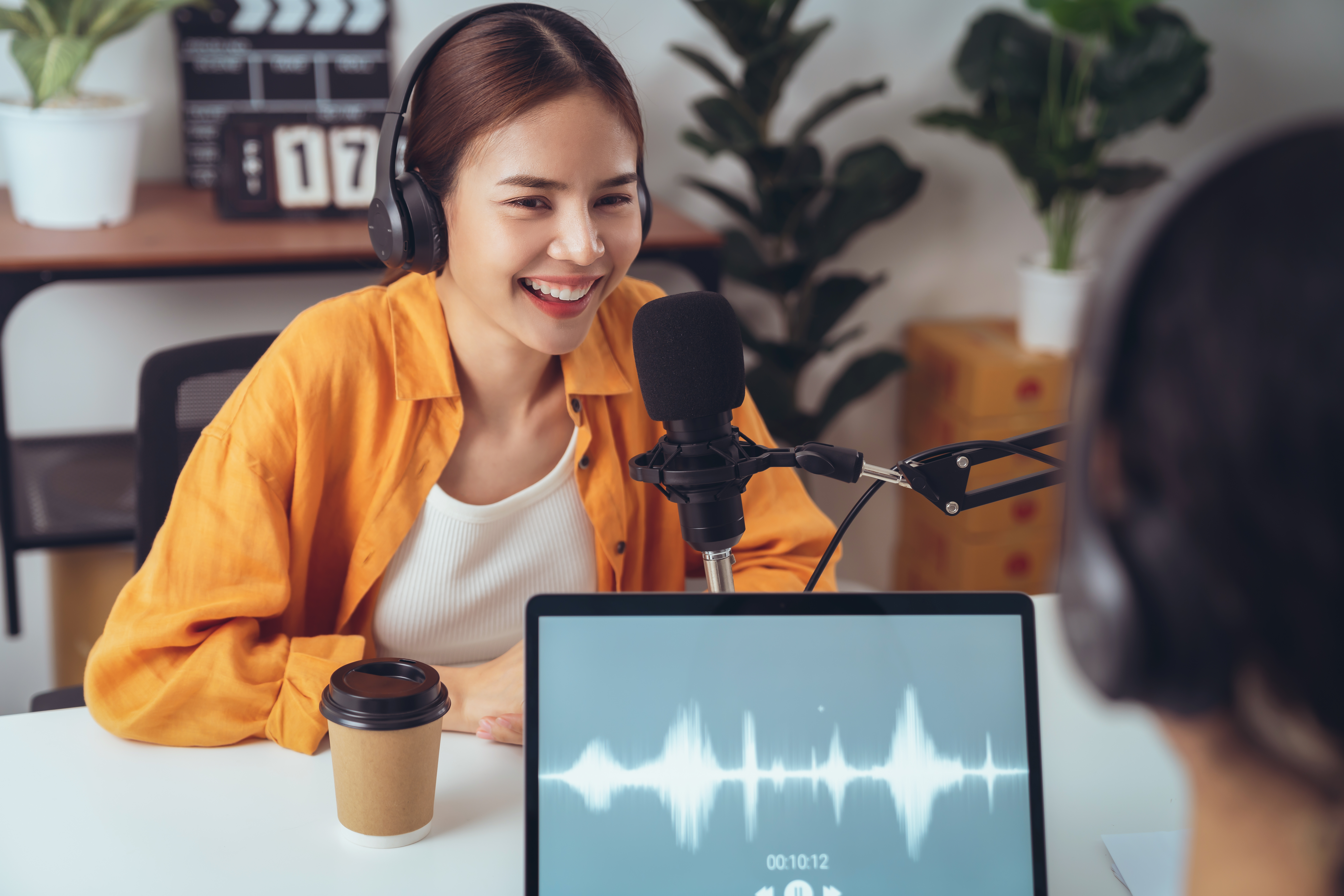 Young Asian woman use microphones wear headphones with laptop record podcast interview for radio