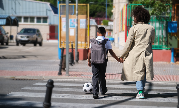 Parent and child holding-hands-on-a-crosswalk with a soccer ball