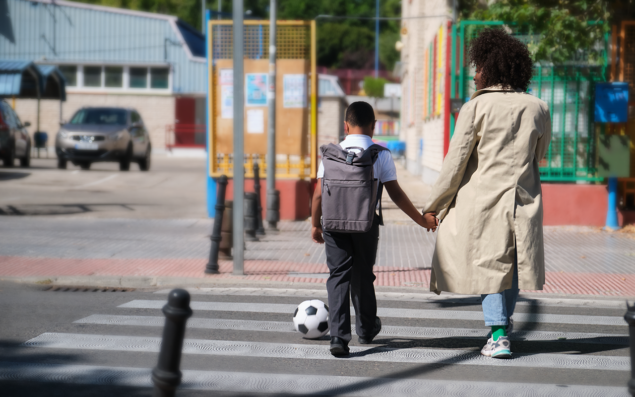 Parent-and-child-holding-hands-on-a-crosswalk-with-a-soccer-ball
