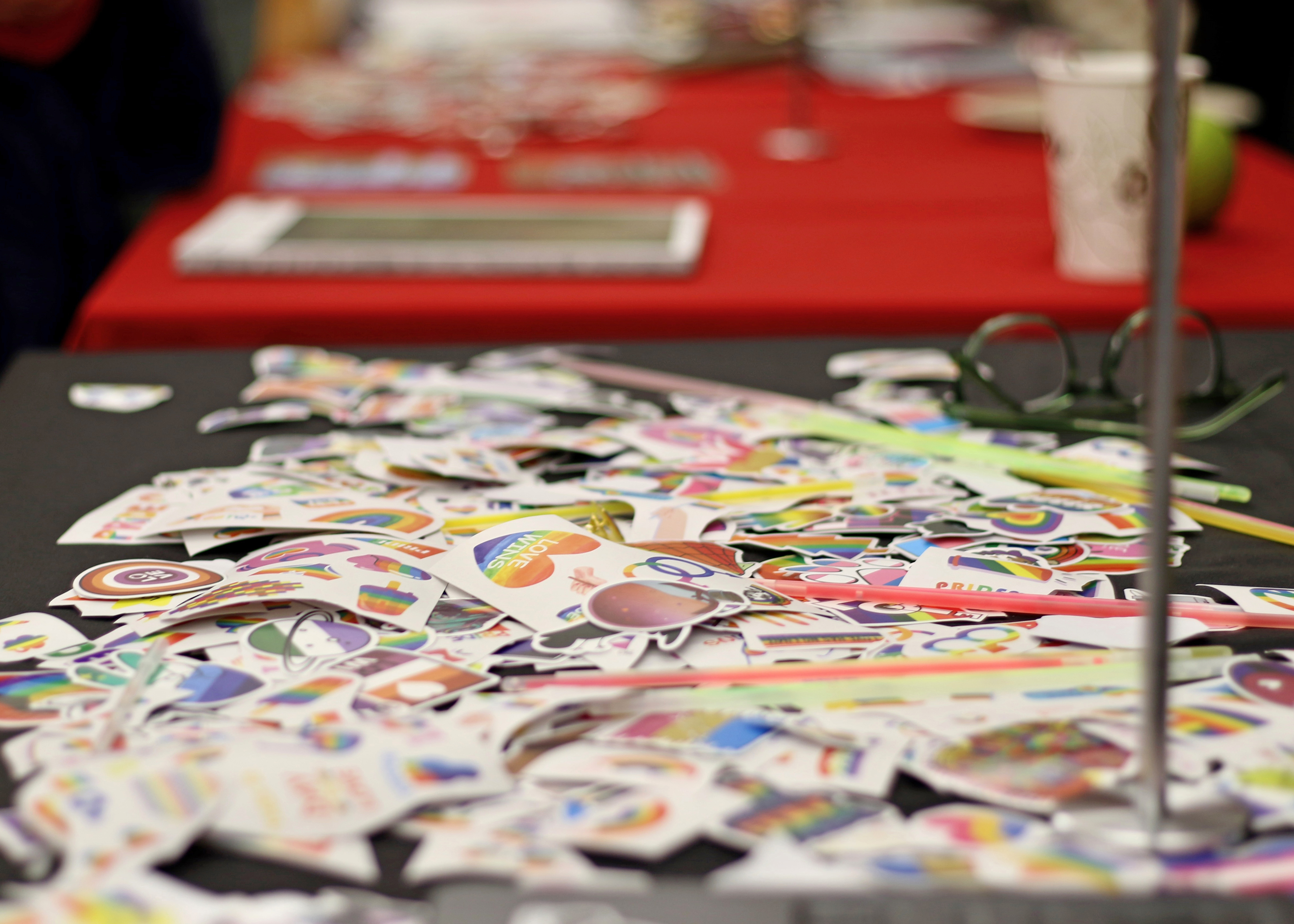 A rainbow, heart-shaped sticker that reads "Love Wins" sits atop a pile of Pride-related stickers.