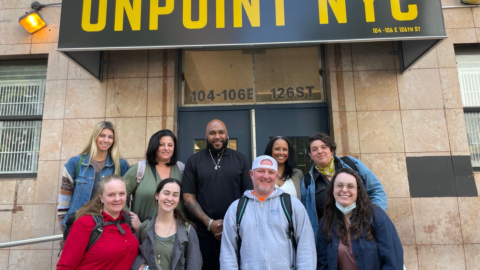 Team members from BUSSW, BMC and OnPoint NYC pose in front of OnPoint NYC building