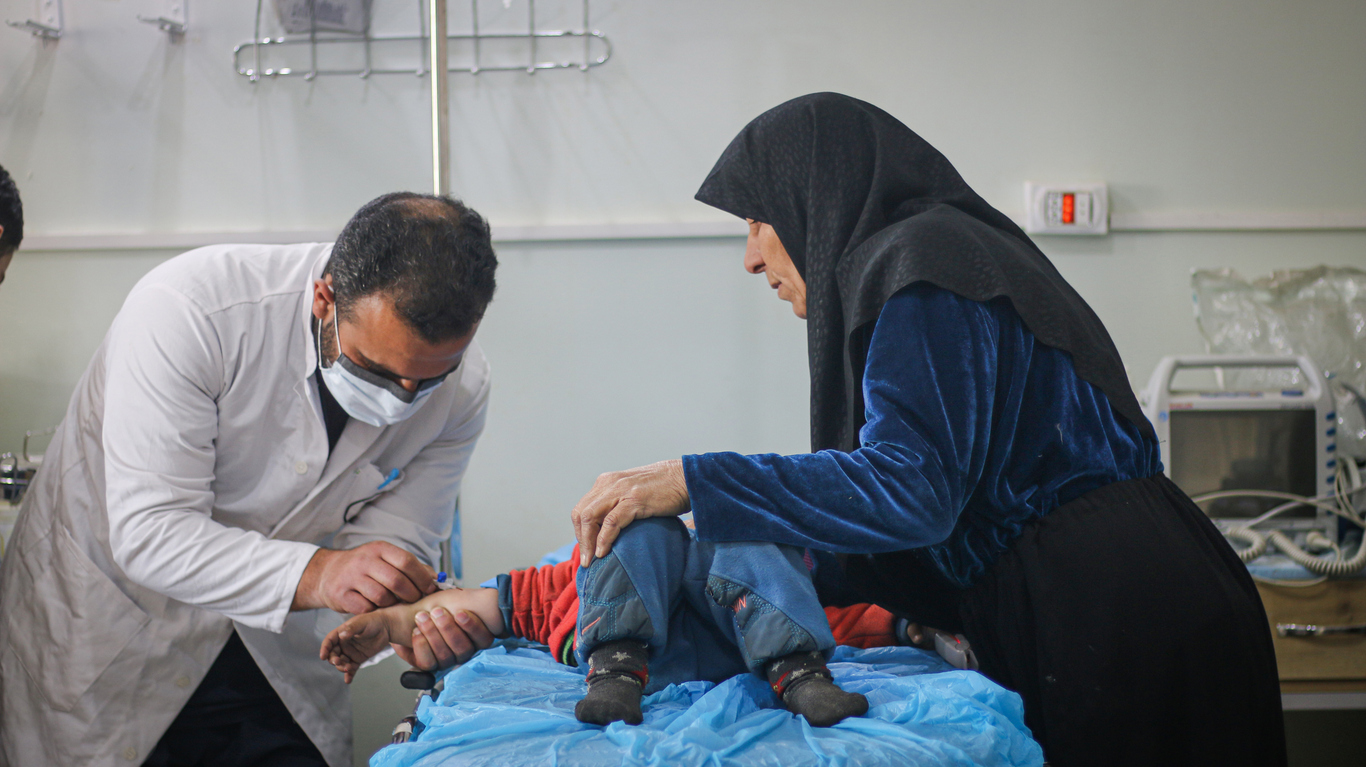 a doctor treats a child while their mother watches in Aleppo, Syria