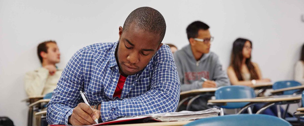A Boston University student taking notes in a classroom - Adults & Professionals Registration