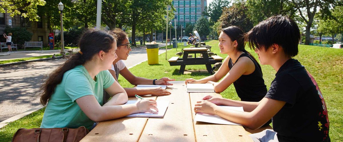 A group of students gathered at a picnic table on the BU Beach