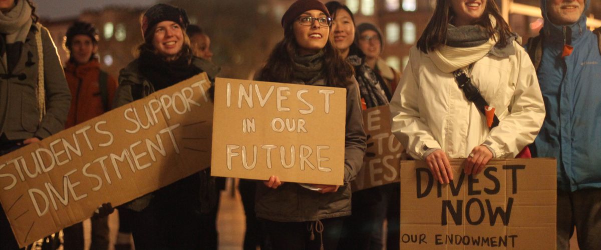 Students hold posters in support of Divestment at DivestBU Rally