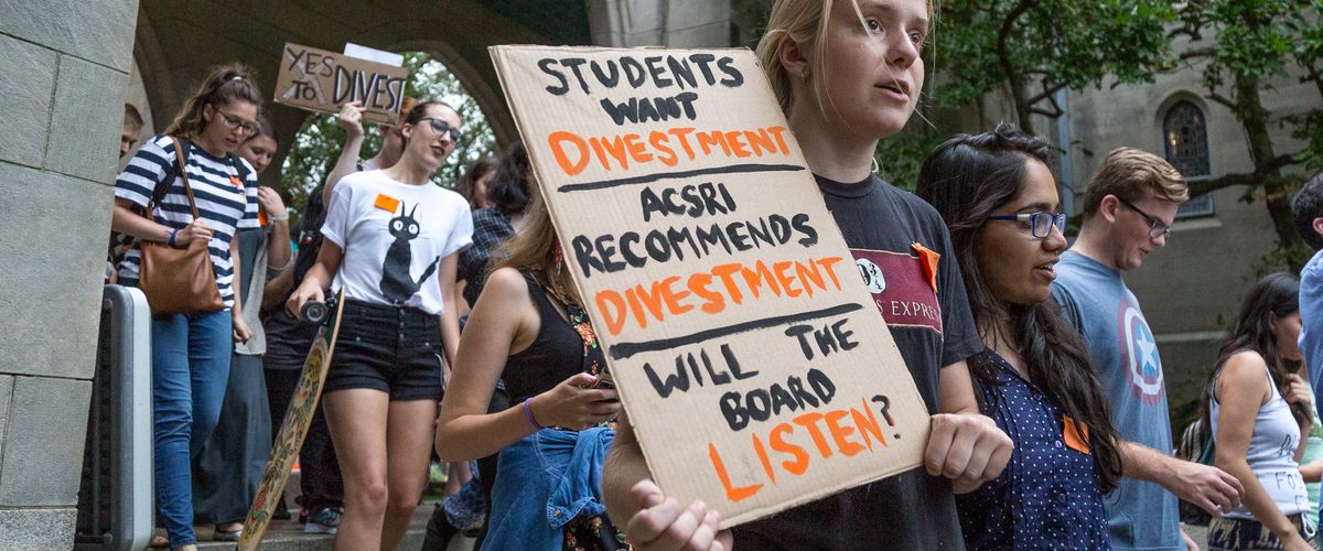 Student holds sign urging for divestment at DIvestBU rally