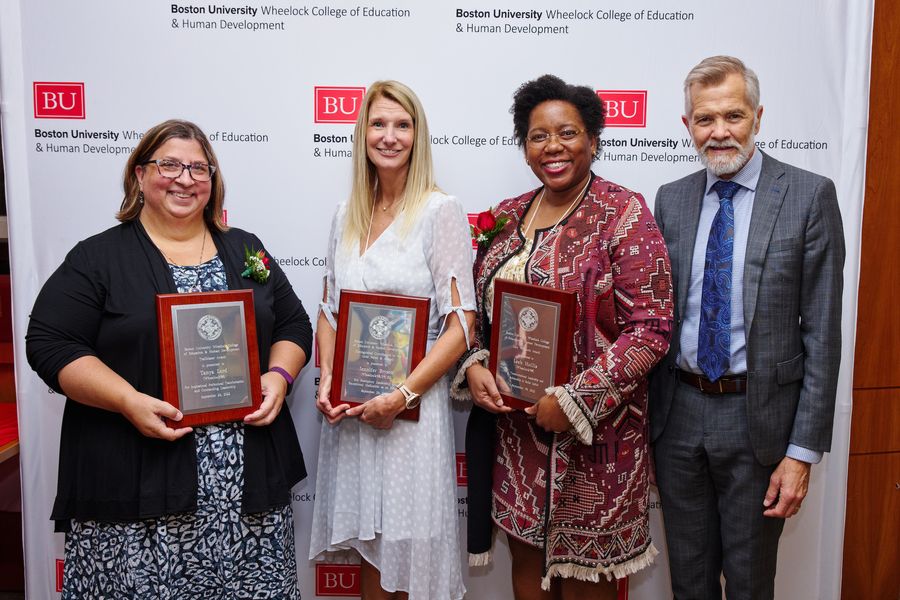 Three Alumni Awardees standing next to Dean David Chard with their awards