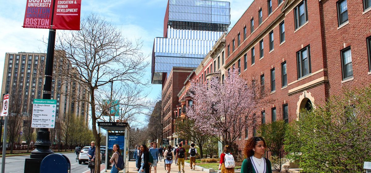 Exterior shot of brick building on city street with pink blooming trees