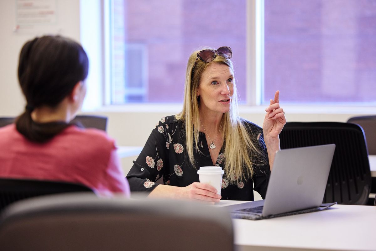 Jen Bryson talking to students sitting infront of a computer