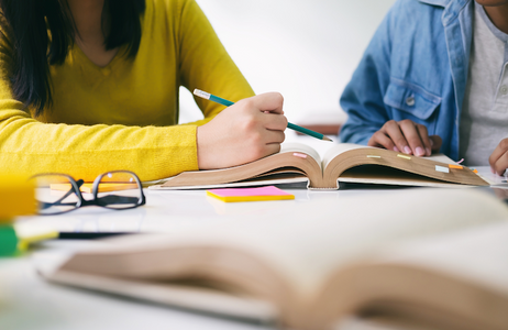 Hands of teach and student studying from books