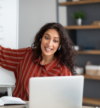 teacher pointing to while board speaking to computer
