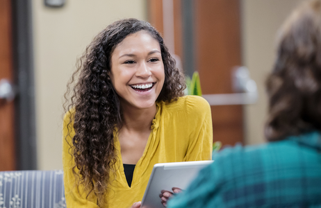 Female student with brown curly hair talking with patient
