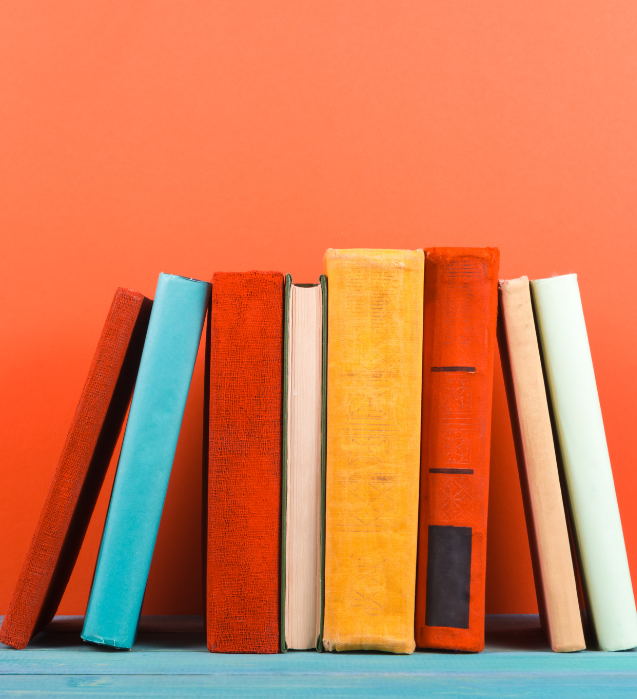 Books stacked up against each other agains coral colored backdrop