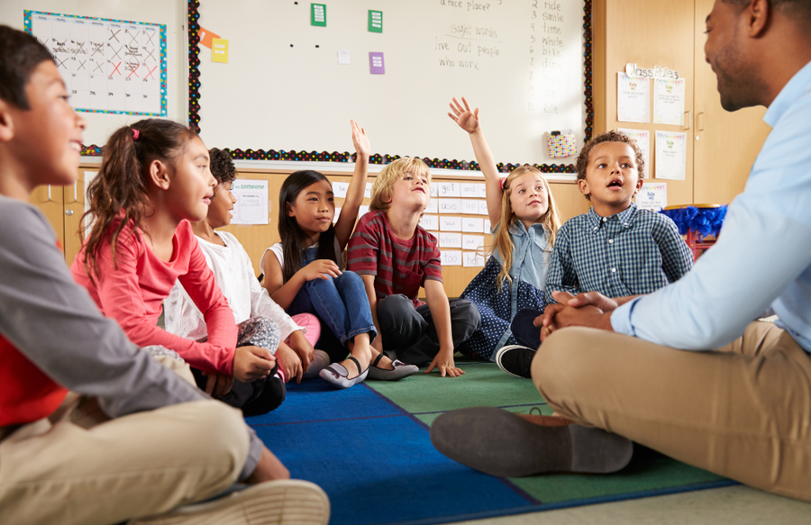 elementary students in circle around male teacher