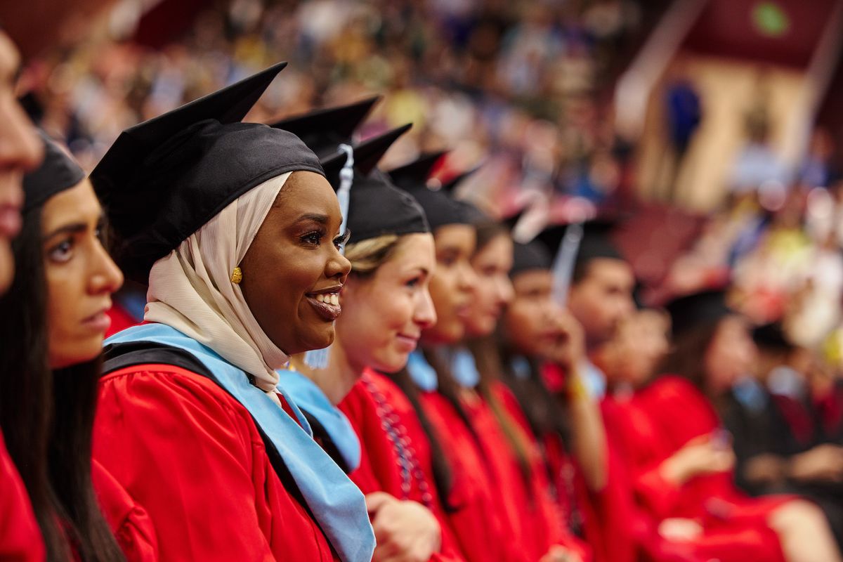 Graduating students look foward smiling towards commencement speaker