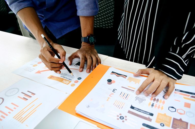 hands of people looking over charts and graphs of a research project