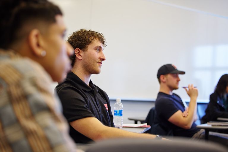 Three male students look forrward to a speaking profession in a class