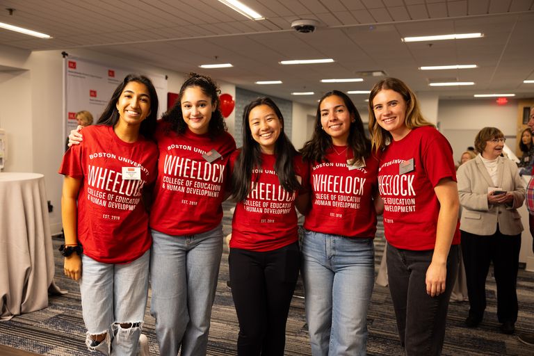 a group of female undergraduate students smiling wearing red BU Wheelock T Shirts