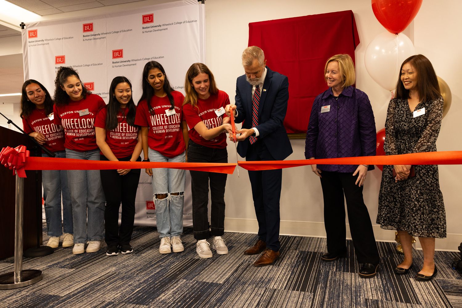 a group of bu wheelock students with Dean David Chard & Faculty cutting a ribbon at the grand opening of new lobby