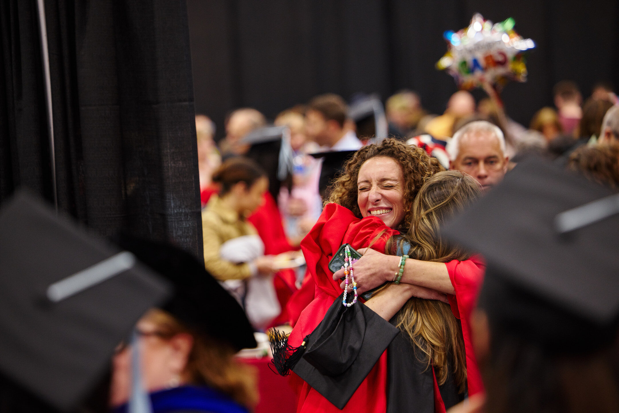 student at commencement embracing audience member out of celebration