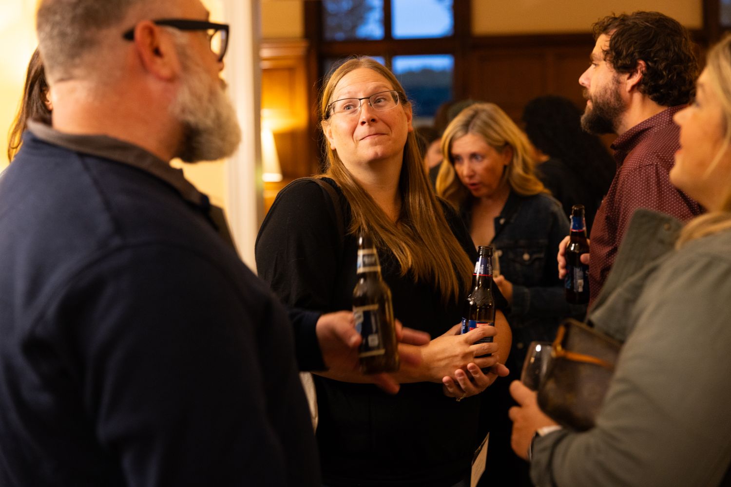 female alumna holding a beer looking at fellow alum at the alumni dinner