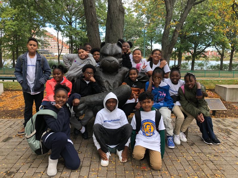 Shows a group of young students sitting at the BU terrier bench