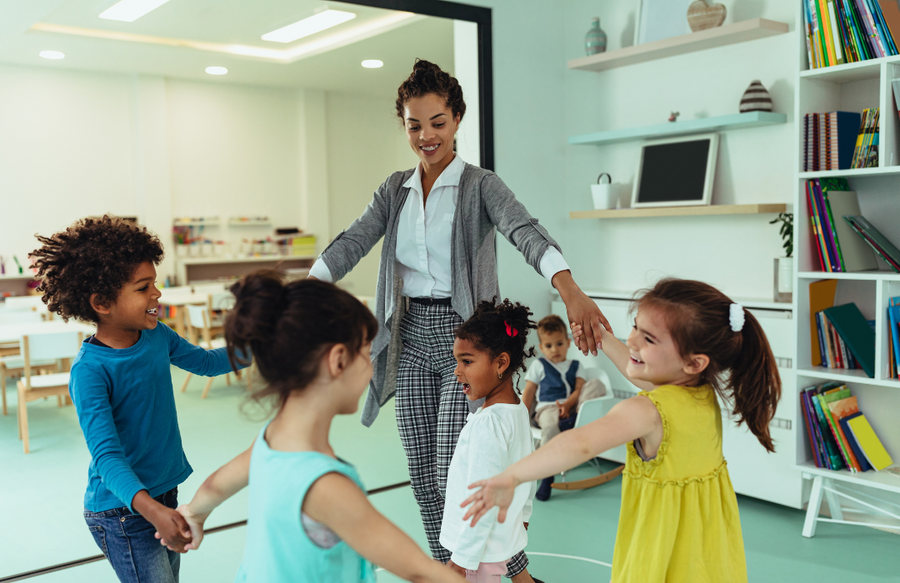 Shows a teacher in a circle with four children