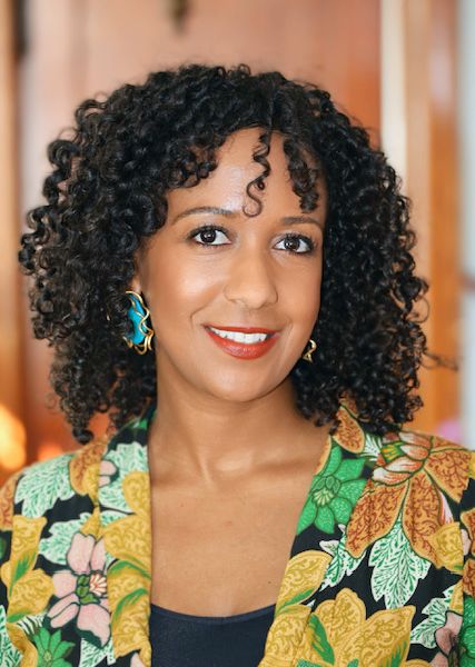 Shows Jalene Tamerat, a woman with curly dark hair wearing a multicolored top