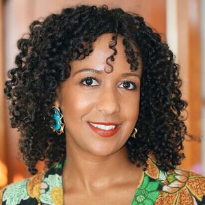 Shows Jalene Tamerat, a woman with curly dark hair wearing a multicolored top