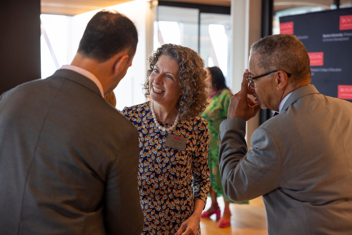 Dean Penny Bishop smiling talking with two men